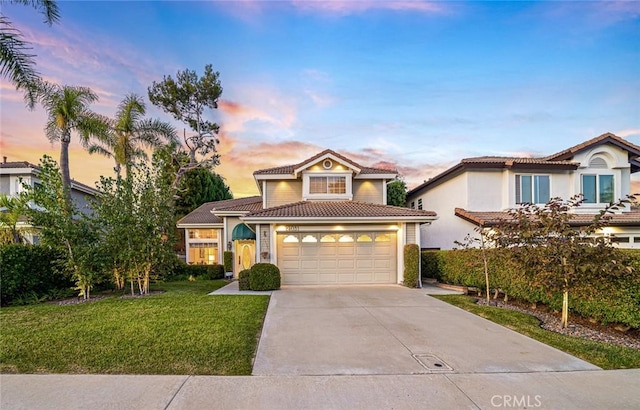 mediterranean / spanish house with a garage and a lawn