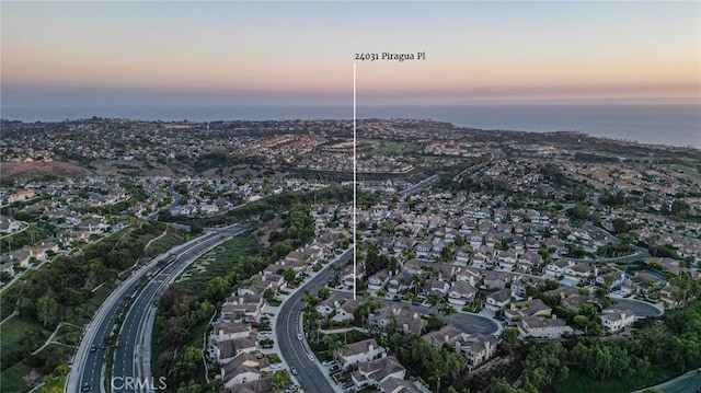 aerial view at dusk featuring a water view