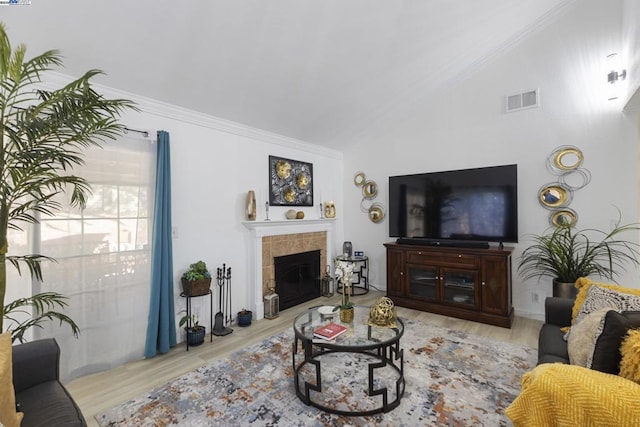 living room with light wood-type flooring, lofted ceiling, and a tile fireplace