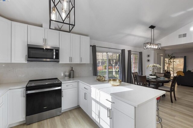 kitchen featuring white cabinetry, decorative light fixtures, backsplash, and appliances with stainless steel finishes