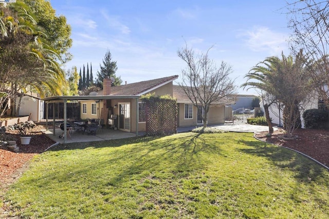 rear view of house with a sunroom, a lawn, and a patio