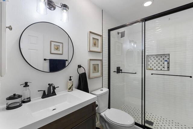 bathroom with walk in shower, vanity, and toilet