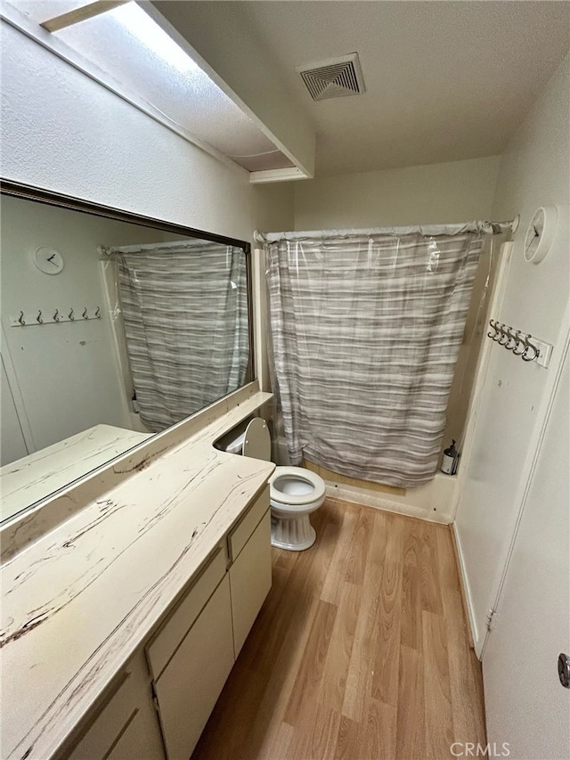 full bathroom featuring vanity, hardwood / wood-style flooring, toilet, and shower / bathtub combination with curtain