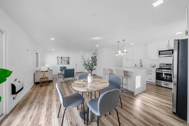 dining area with heating unit, light hardwood / wood-style flooring, and sink