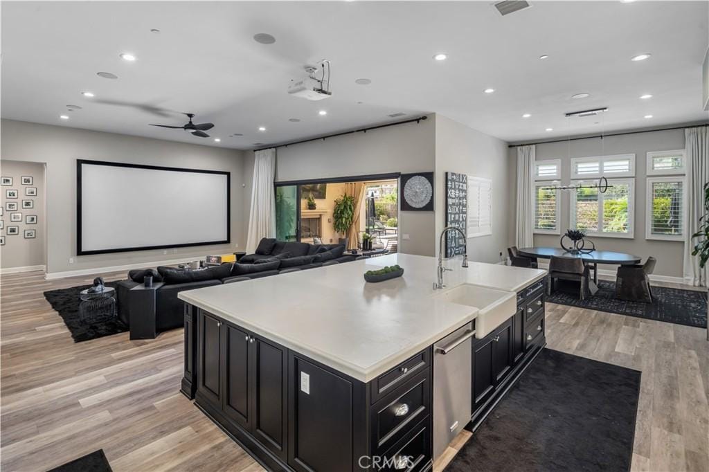 cinema with ceiling fan, sink, a wealth of natural light, and light hardwood / wood-style flooring