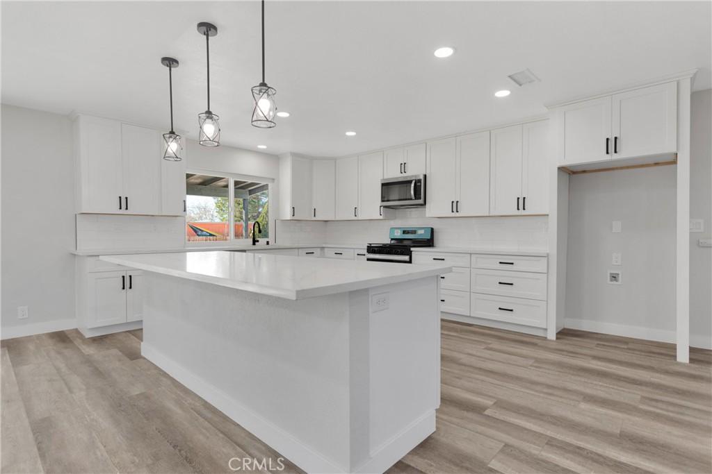 kitchen with white cabinets, appliances with stainless steel finishes, a center island, and tasteful backsplash