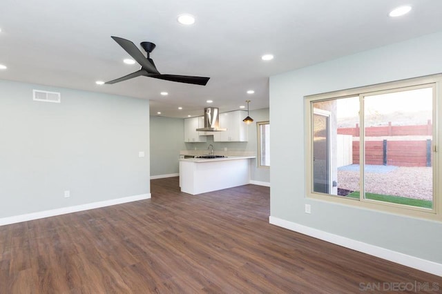 unfurnished living room featuring ceiling fan, dark wood-type flooring, and sink