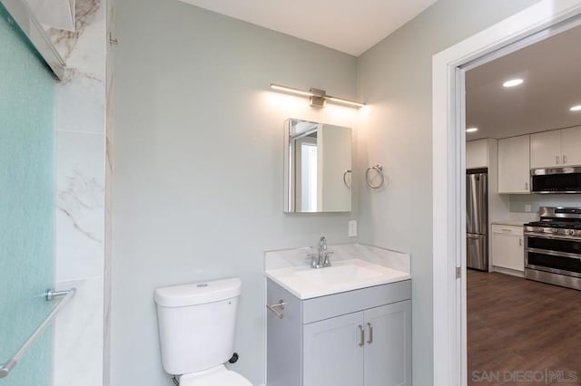 bathroom with toilet, hardwood / wood-style floors, and vanity