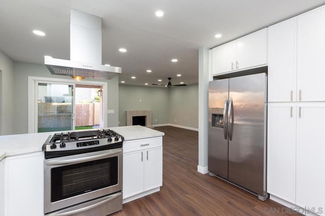 kitchen with ceiling fan, white cabinets, island range hood, and stainless steel appliances