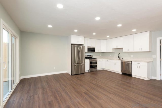 kitchen with appliances with stainless steel finishes, sink, white cabinetry, and dark hardwood / wood-style floors