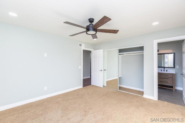 unfurnished bedroom with carpet, connected bathroom, sink, a closet, and ceiling fan