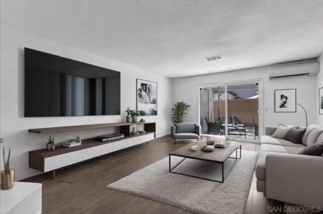 living room with dark wood-type flooring and an AC wall unit