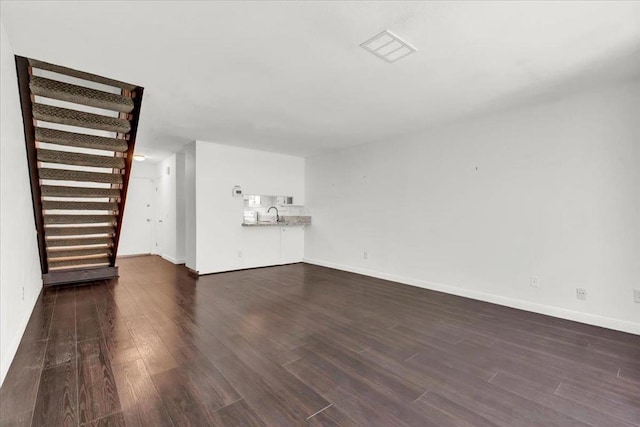 unfurnished living room featuring dark wood-type flooring and sink