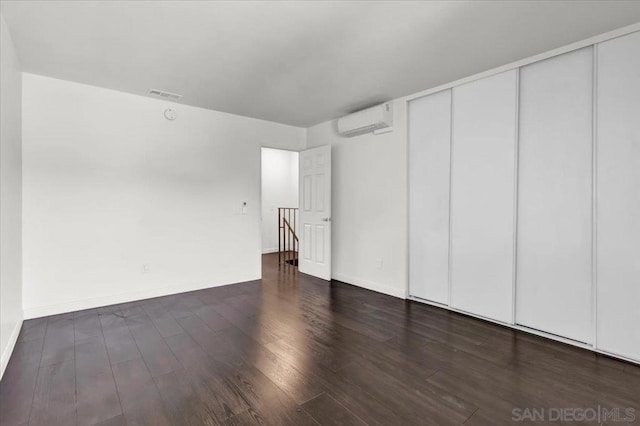 empty room featuring an AC wall unit and dark hardwood / wood-style flooring