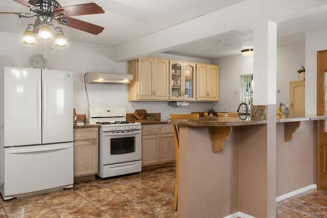 kitchen featuring exhaust hood, kitchen peninsula, light brown cabinets, white appliances, and a breakfast bar