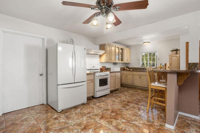 kitchen with light brown cabinets, a breakfast bar, extractor fan, and white appliances