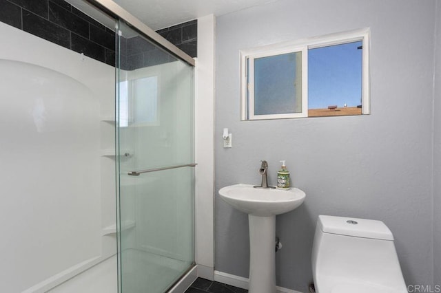 bathroom featuring toilet, sink, and a shower with door