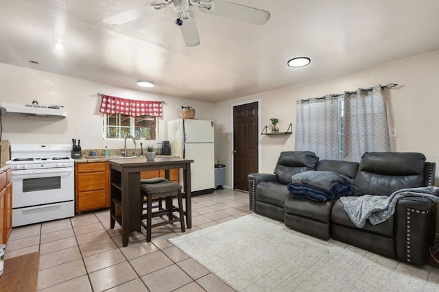 interior space with ceiling fan, white appliances, light tile patterned flooring, range hood, and sink