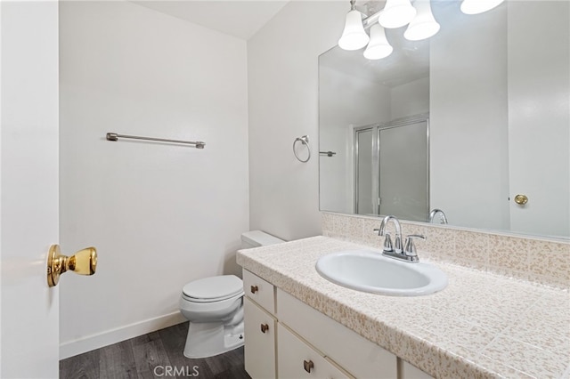 bathroom featuring toilet, hardwood / wood-style flooring, vanity, and an enclosed shower