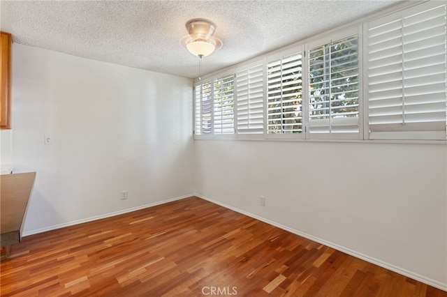 spare room with hardwood / wood-style floors and a textured ceiling