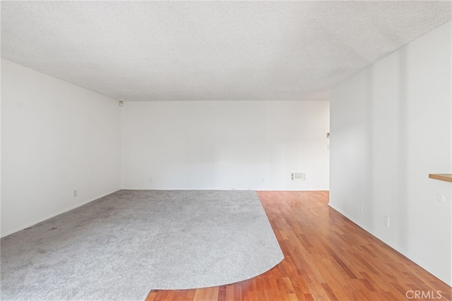 spare room with a textured ceiling and light hardwood / wood-style flooring