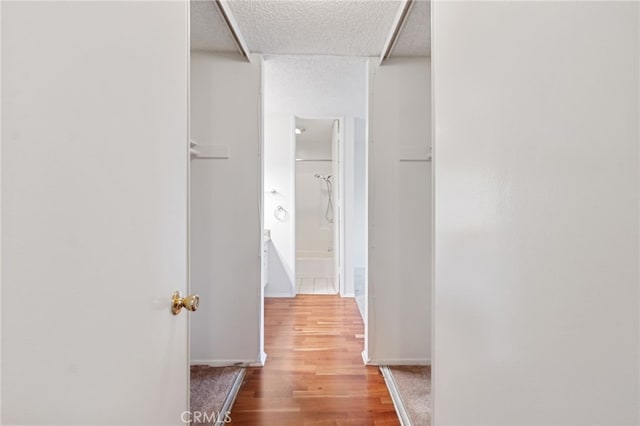 corridor with hardwood / wood-style flooring and a textured ceiling