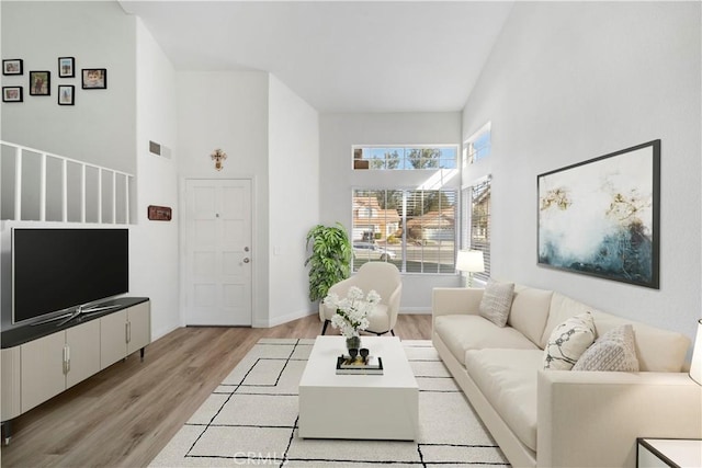 living room with a towering ceiling and light wood-type flooring