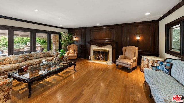 living room with crown molding, a premium fireplace, and light wood-type flooring