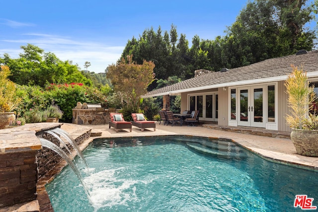 view of pool with pool water feature, a patio area, and french doors