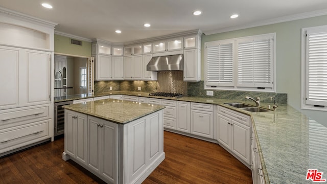 kitchen featuring a center island, sink, white cabinetry, wall chimney exhaust hood, and beverage cooler