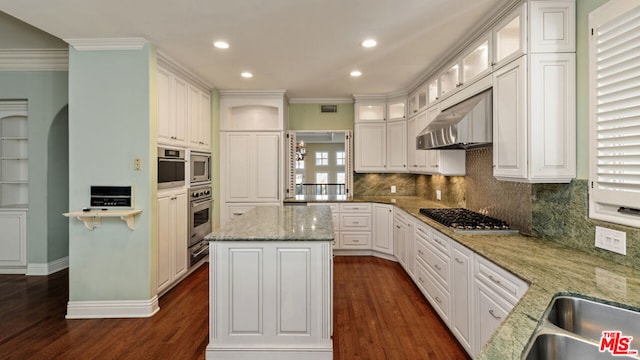 kitchen with a center island, light stone countertops, stainless steel appliances, white cabinets, and dark hardwood / wood-style flooring