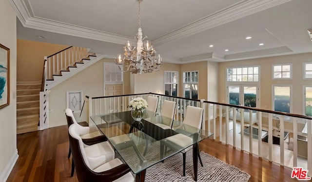 dining space with ornamental molding, dark hardwood / wood-style flooring, a tray ceiling, and a notable chandelier