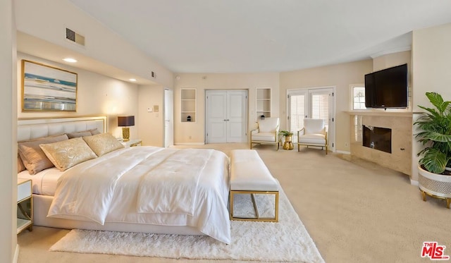 bedroom featuring light colored carpet and a fireplace