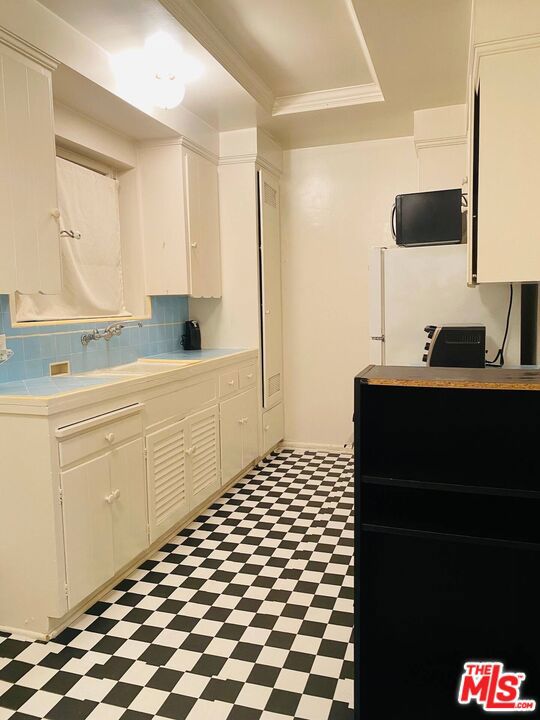 kitchen featuring white cabinets, decorative backsplash, sink, and ornamental molding