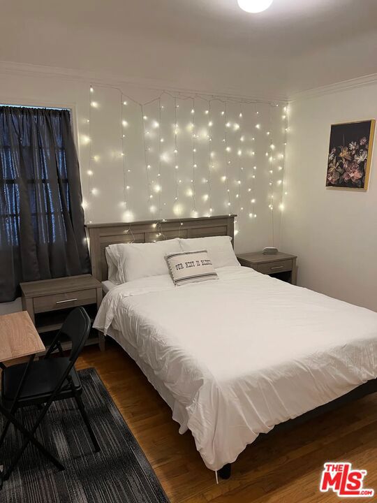 bedroom featuring dark wood-type flooring and crown molding