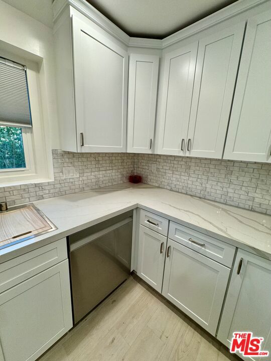 kitchen with decorative backsplash, light hardwood / wood-style flooring, white cabinets, and light stone counters