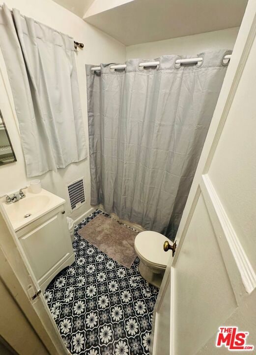 bathroom featuring toilet, walk in shower, and vanity