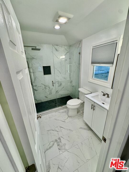 bathroom with a shower with shower door, toilet, and vanity