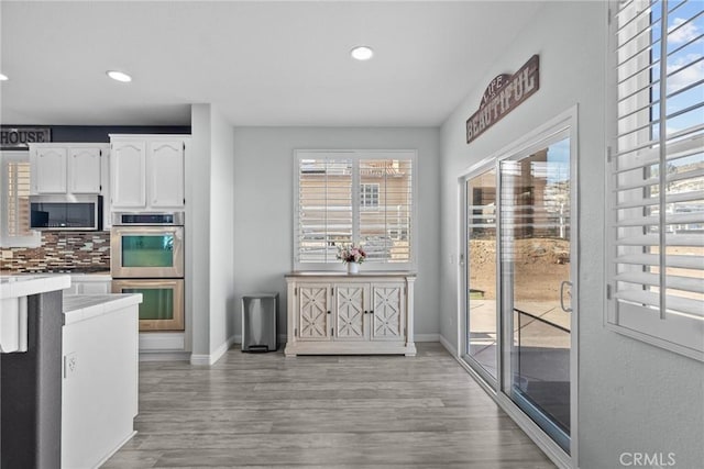 kitchen featuring decorative backsplash, plenty of natural light, stainless steel appliances, and white cabinetry