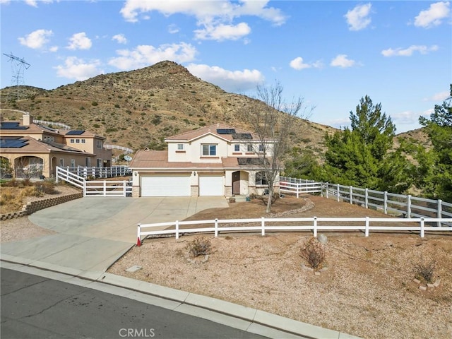 view of front of property featuring a garage, a mountain view, and solar panels