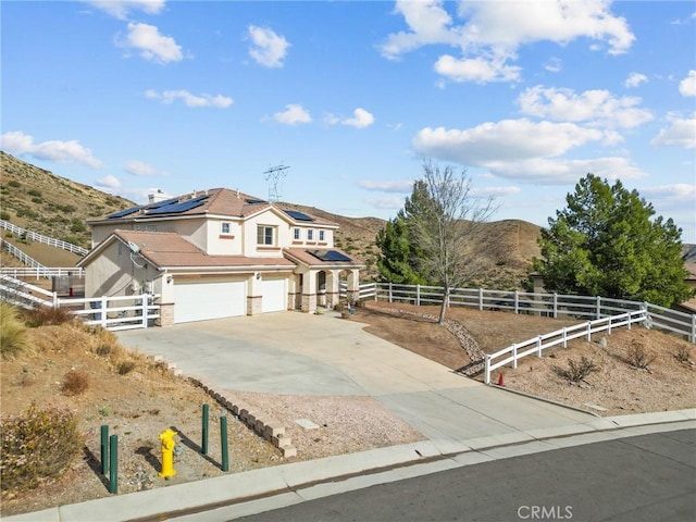 view of front of property featuring a mountain view, a garage, a rural view, and solar panels