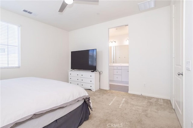 carpeted bedroom with ensuite bath and ceiling fan