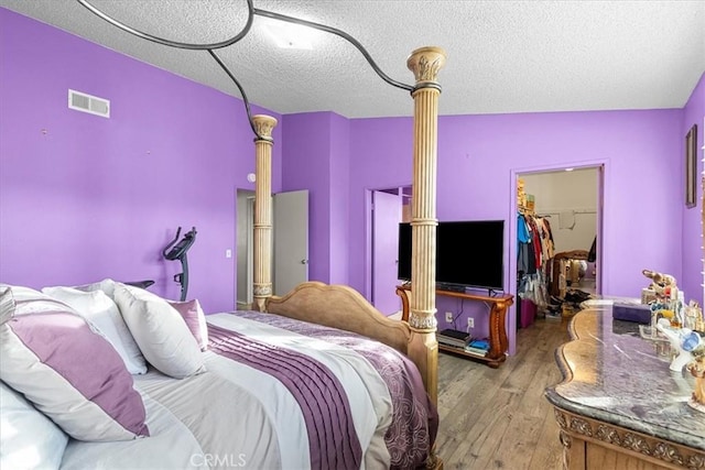 bedroom with lofted ceiling, wood-type flooring, a spacious closet, a textured ceiling, and a closet