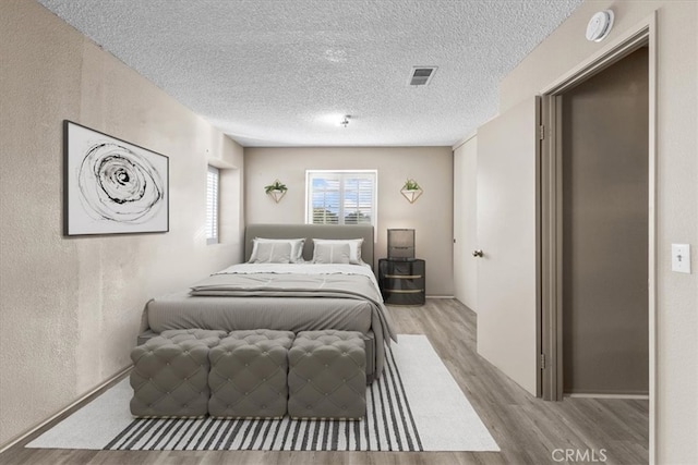 bedroom featuring a textured ceiling and light hardwood / wood-style flooring