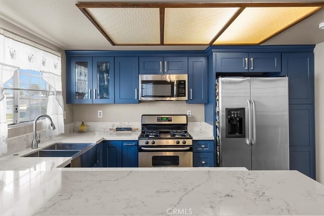 kitchen featuring light stone countertops, stainless steel appliances, blue cabinets, and sink