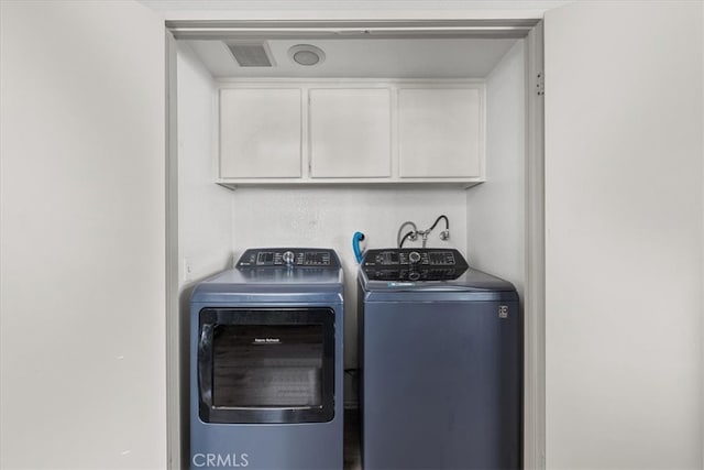 clothes washing area with cabinets and independent washer and dryer