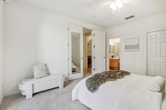 carpeted bedroom with ensuite bath, ceiling fan, and washer / dryer