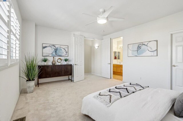 bedroom featuring ceiling fan, light carpet, and ensuite bath