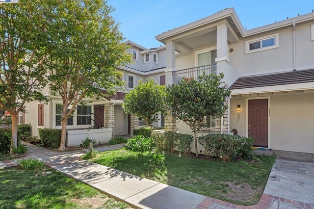 townhome / multi-family property featuring a balcony and a front yard