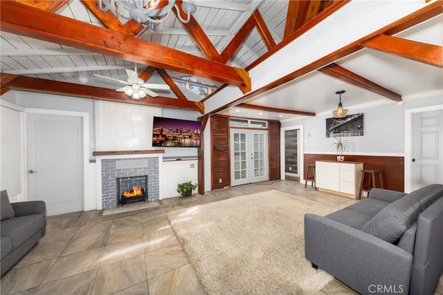 living room with ceiling fan, vaulted ceiling with beams, and a fireplace